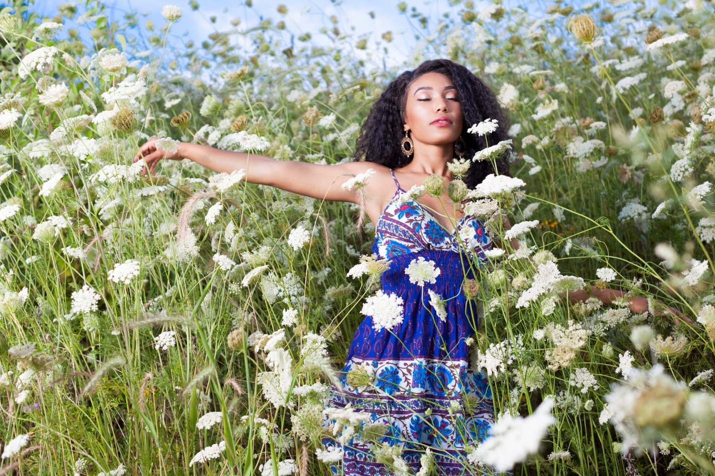 A person in a blue dress standing in a field of white flowers

Description automatically generated with medium confidence