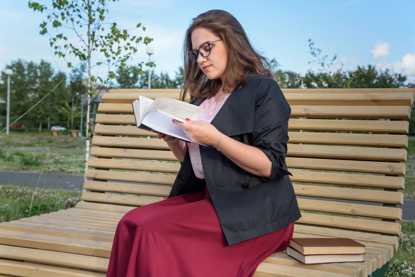 A person sitting on a bench reading a book

Description automatically generated