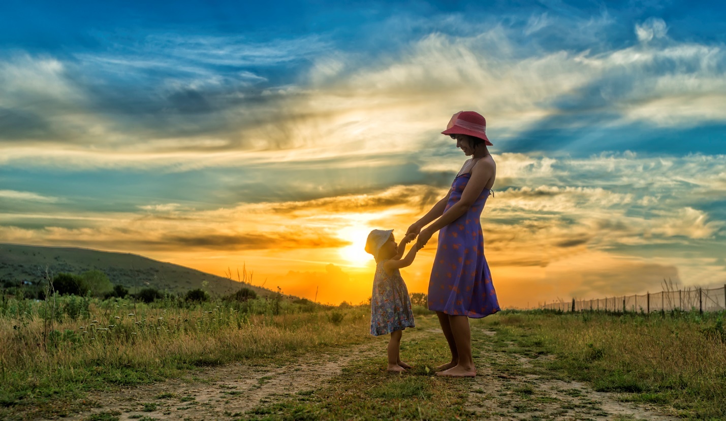 A person and a child walking on a dirt road with the sun setting

Description automatically generated with low confidence