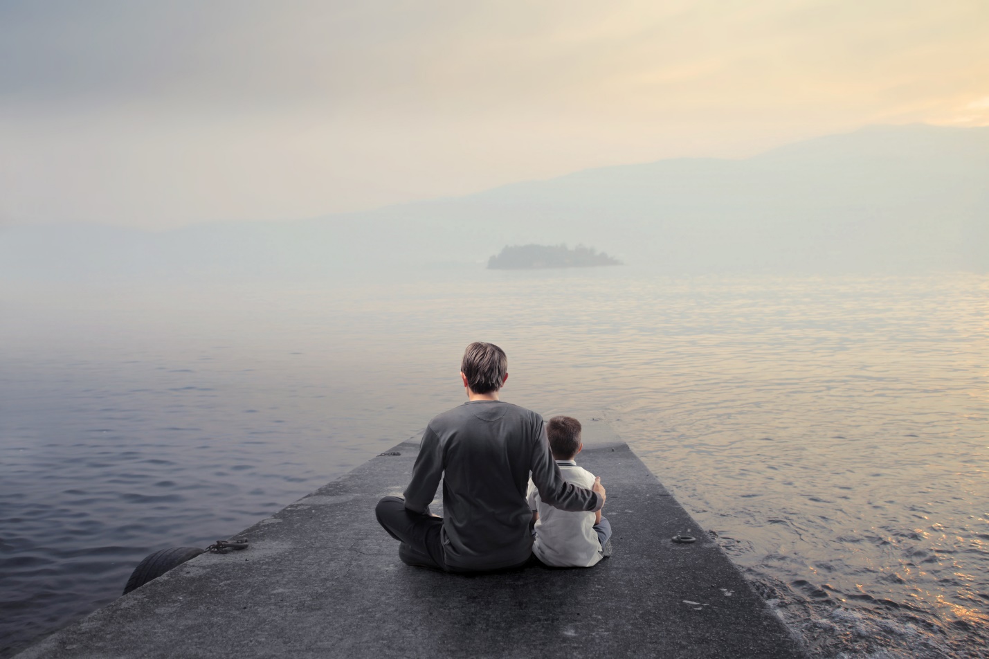 A person and a child sitting on a rock overlooking the ocean

Description automatically generated with low confidence
