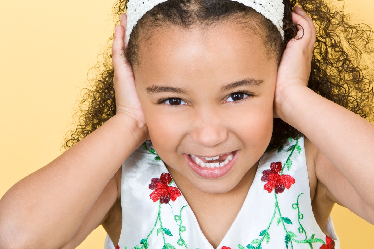 A young child holding her ears

Description automatically generated