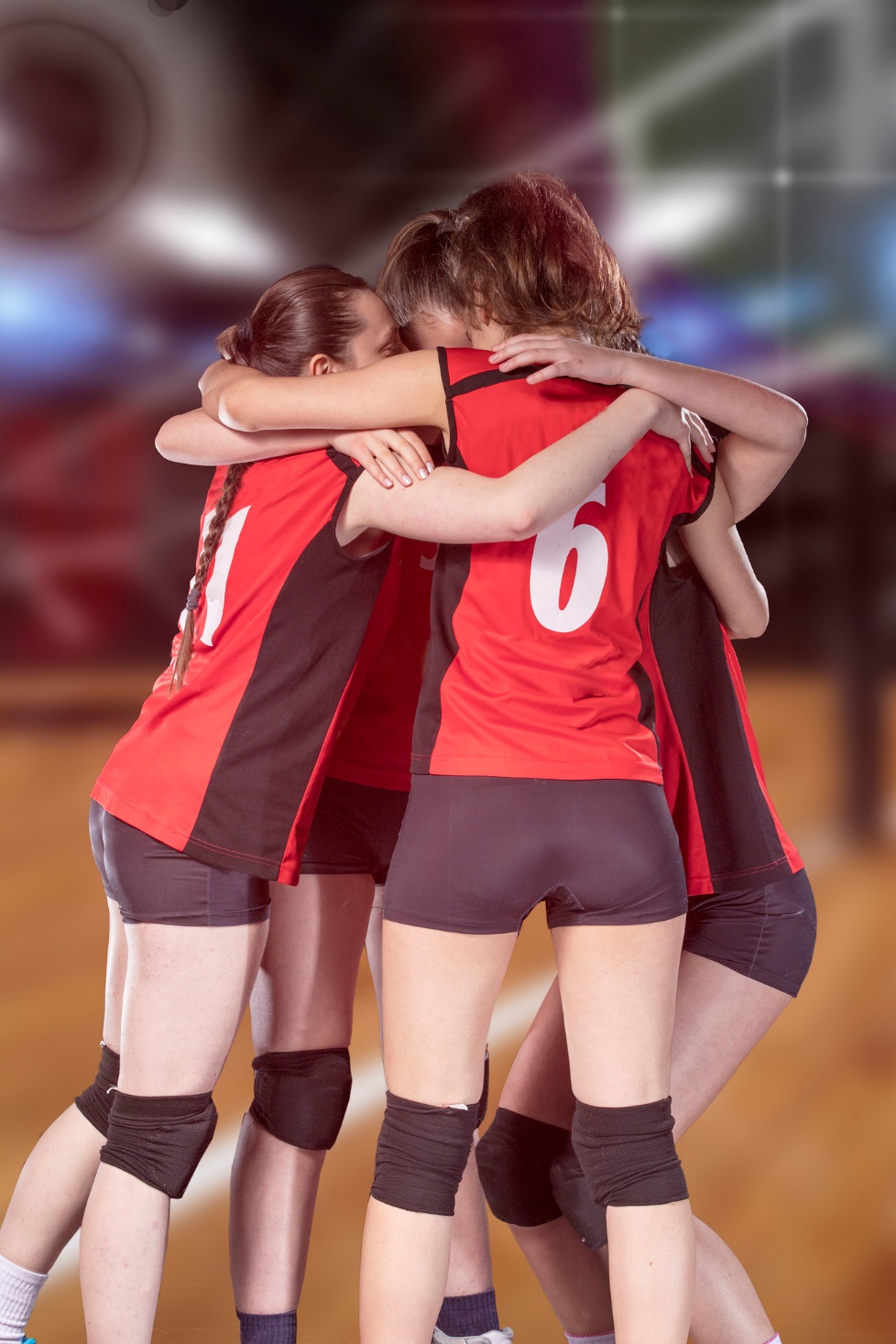 A group of women in sports uniforms hugging

Description automatically generated
