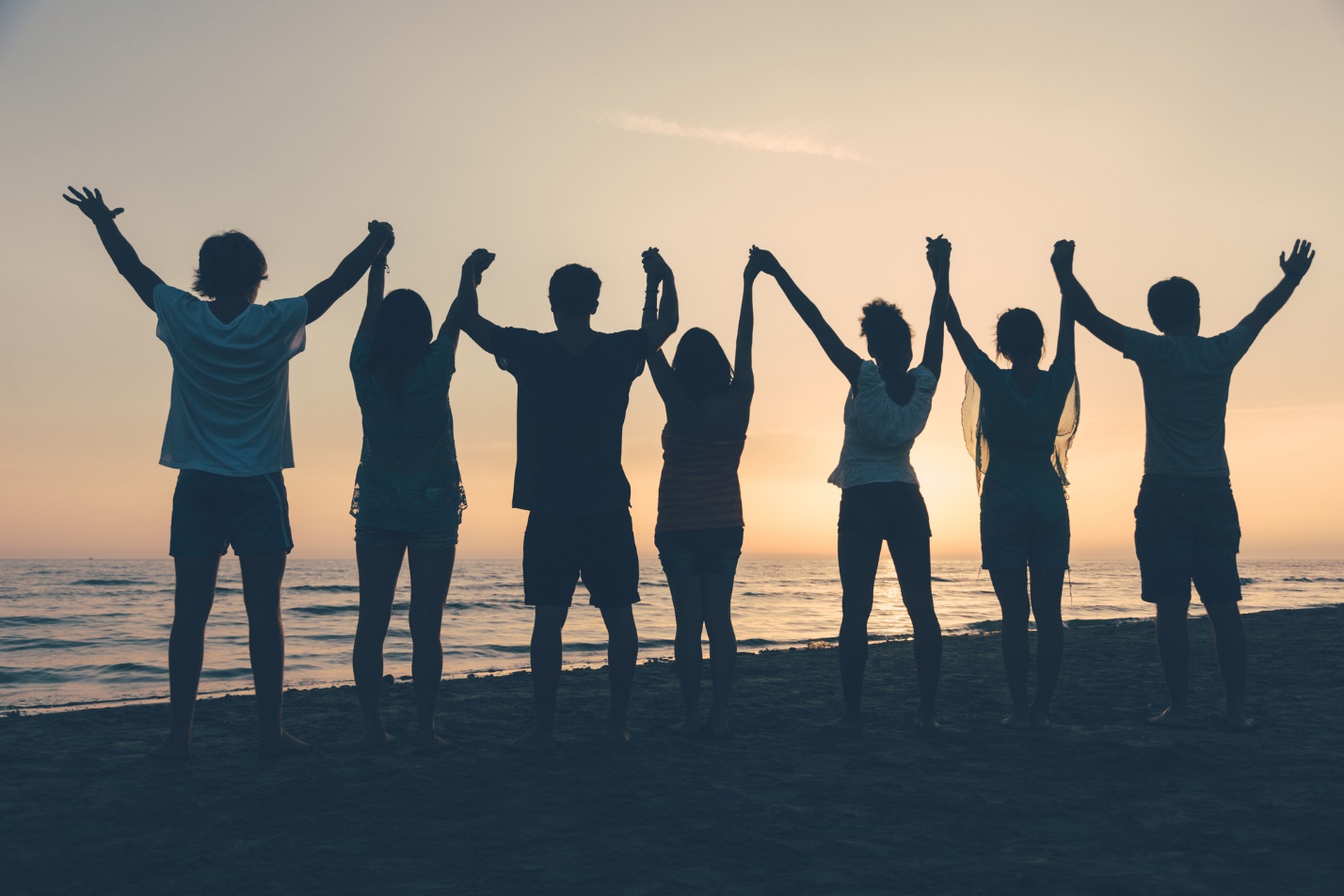A group of people holding hands on a beach

Description automatically generated