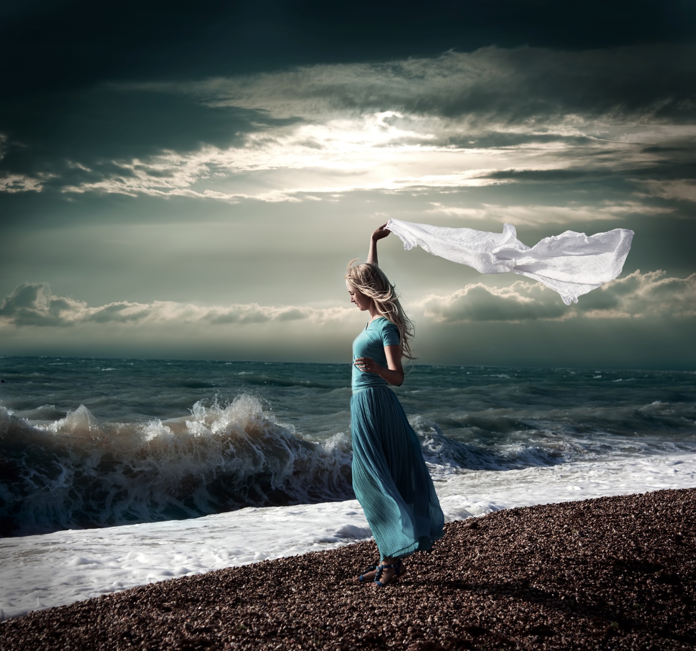 A person in a blue dress on a beach with waves and a white scarf

Description automatically generated