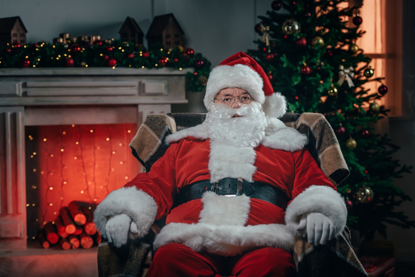 A person in a santa claus garment sitting in a chair

Description automatically generated