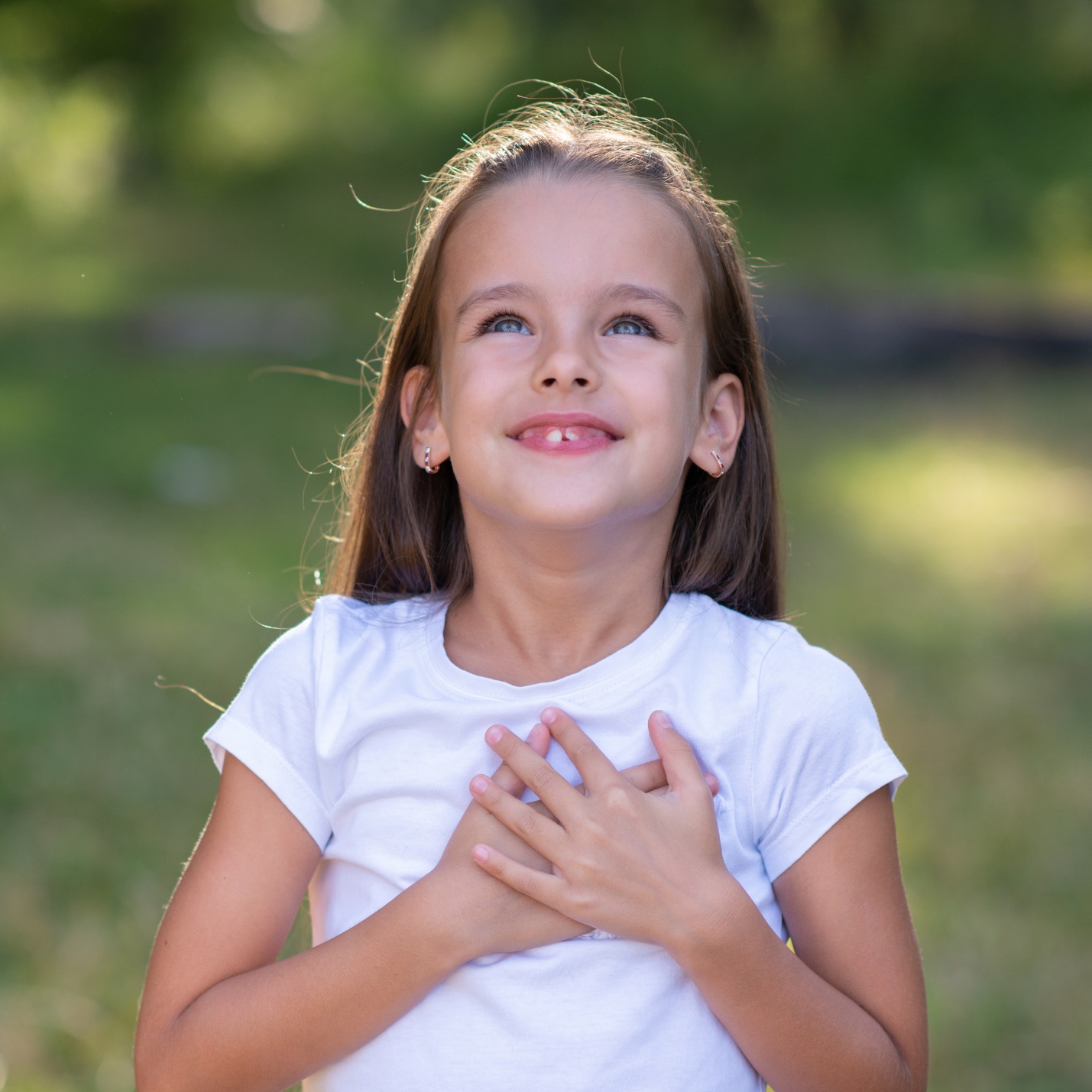 A child holding her hands on her chest

Description automatically generated