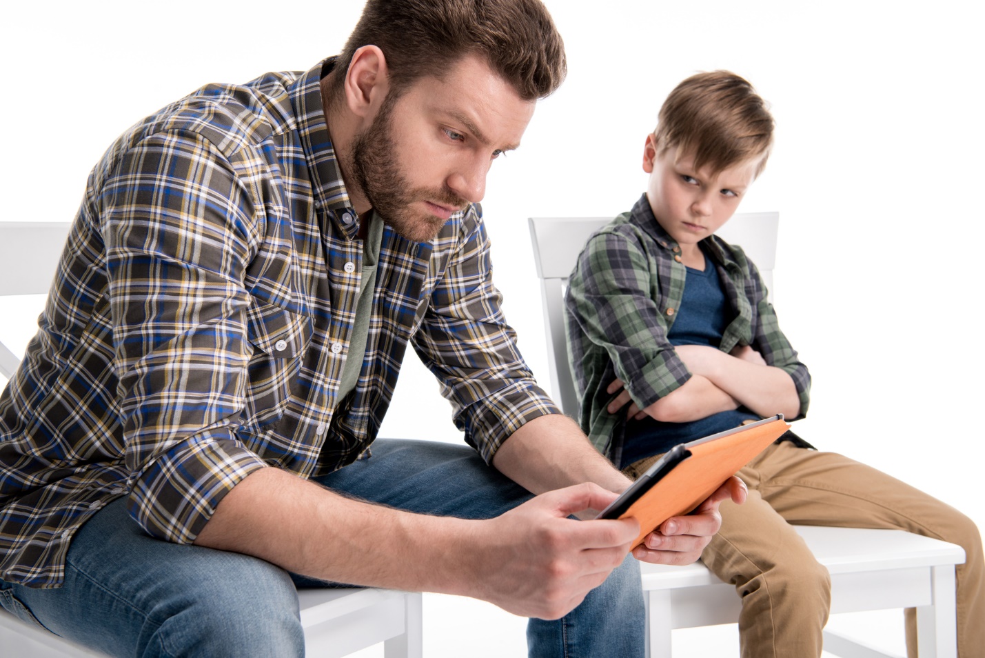 A person and child sitting on chairs looking at tablet

Description automatically generated