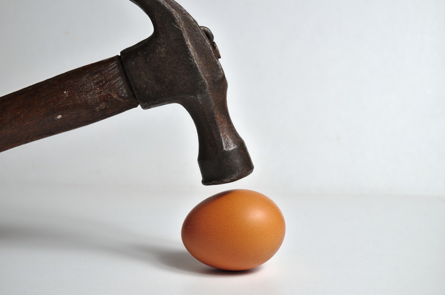 A hammer hitting an egg

Description automatically generated