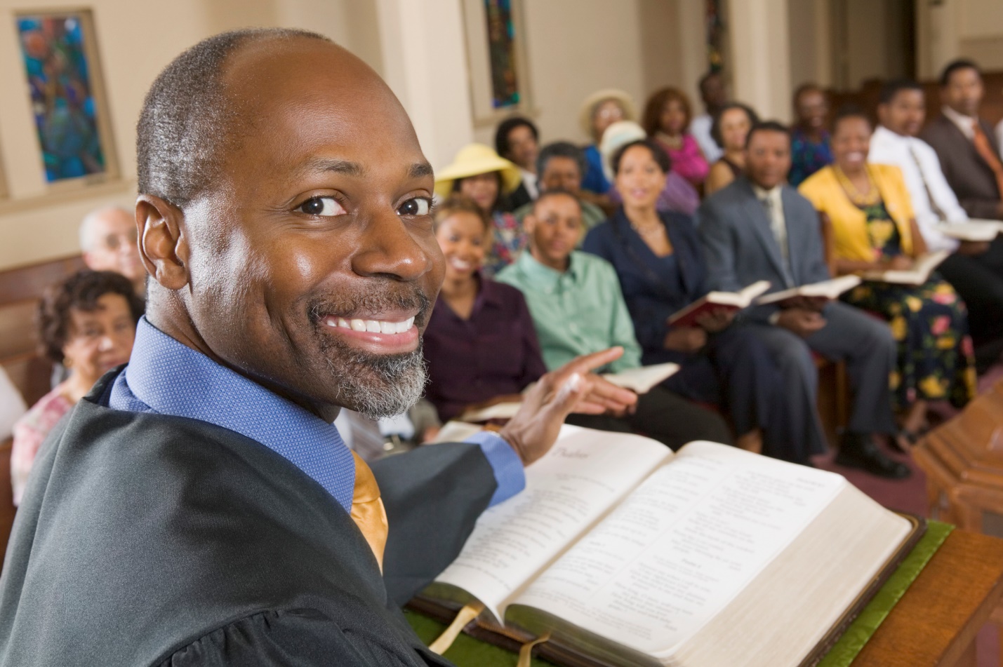 A person in a robe with a group of people in the background

Description automatically generated