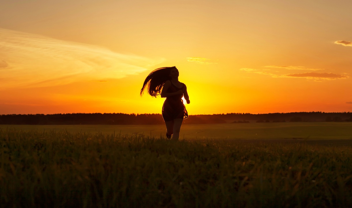 A person running in a field at sunset

Description automatically generated