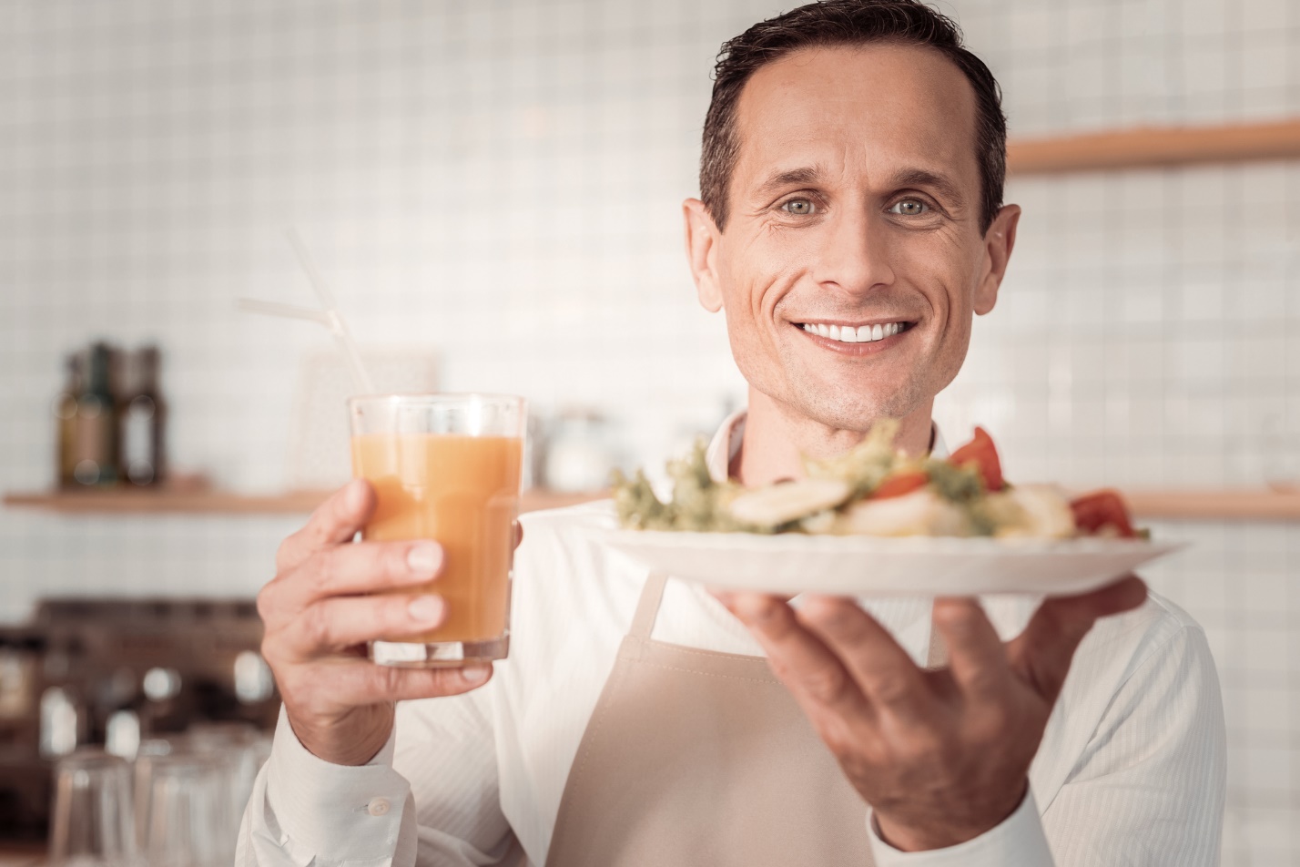 A person holding a plate of food and a glass of juice

Description automatically generated