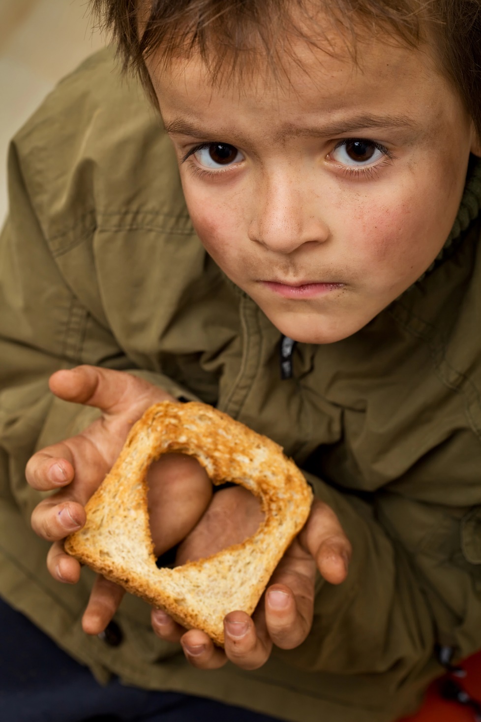 A child holding a piece of bread with a heart cut out

Description automatically generated