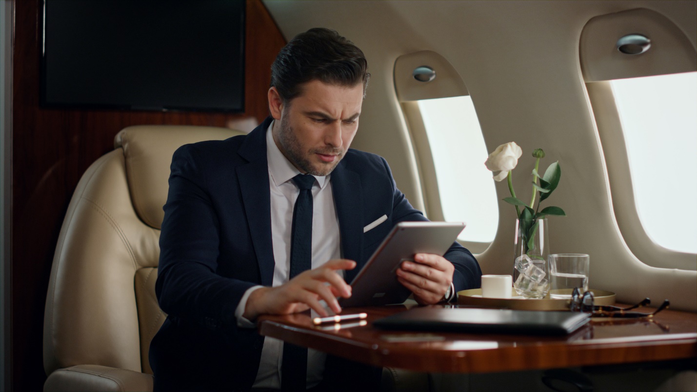 A person in a suit looking at a tablet

Description automatically generated