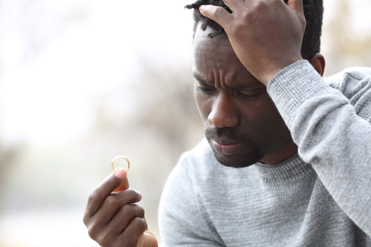 A person holding his head and looking at a ring

Description automatically generated