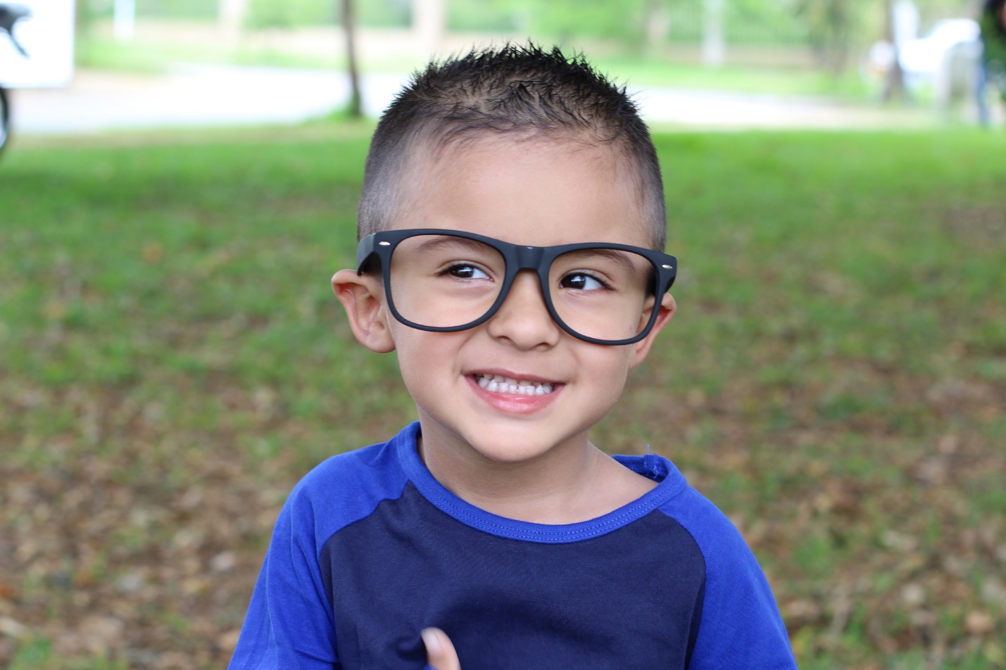 A child wearing glasses and smiling

Description automatically generated