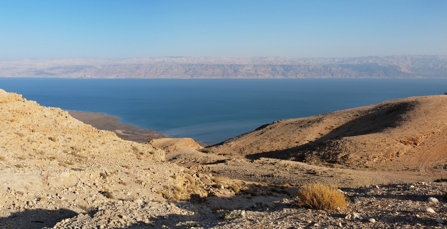 A rocky hills with a body of water in the background

Description automatically generated