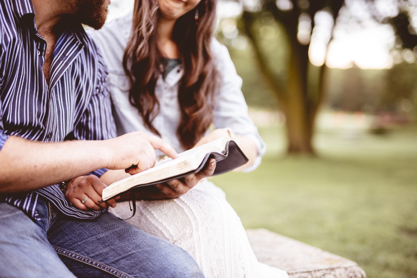 A person and person sitting on a bench reading a book

Description automatically generated