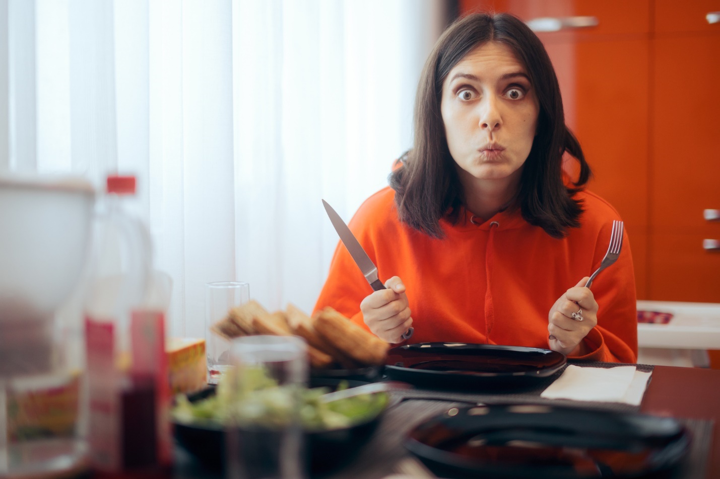 A person holding a knife and fork

Description automatically generated