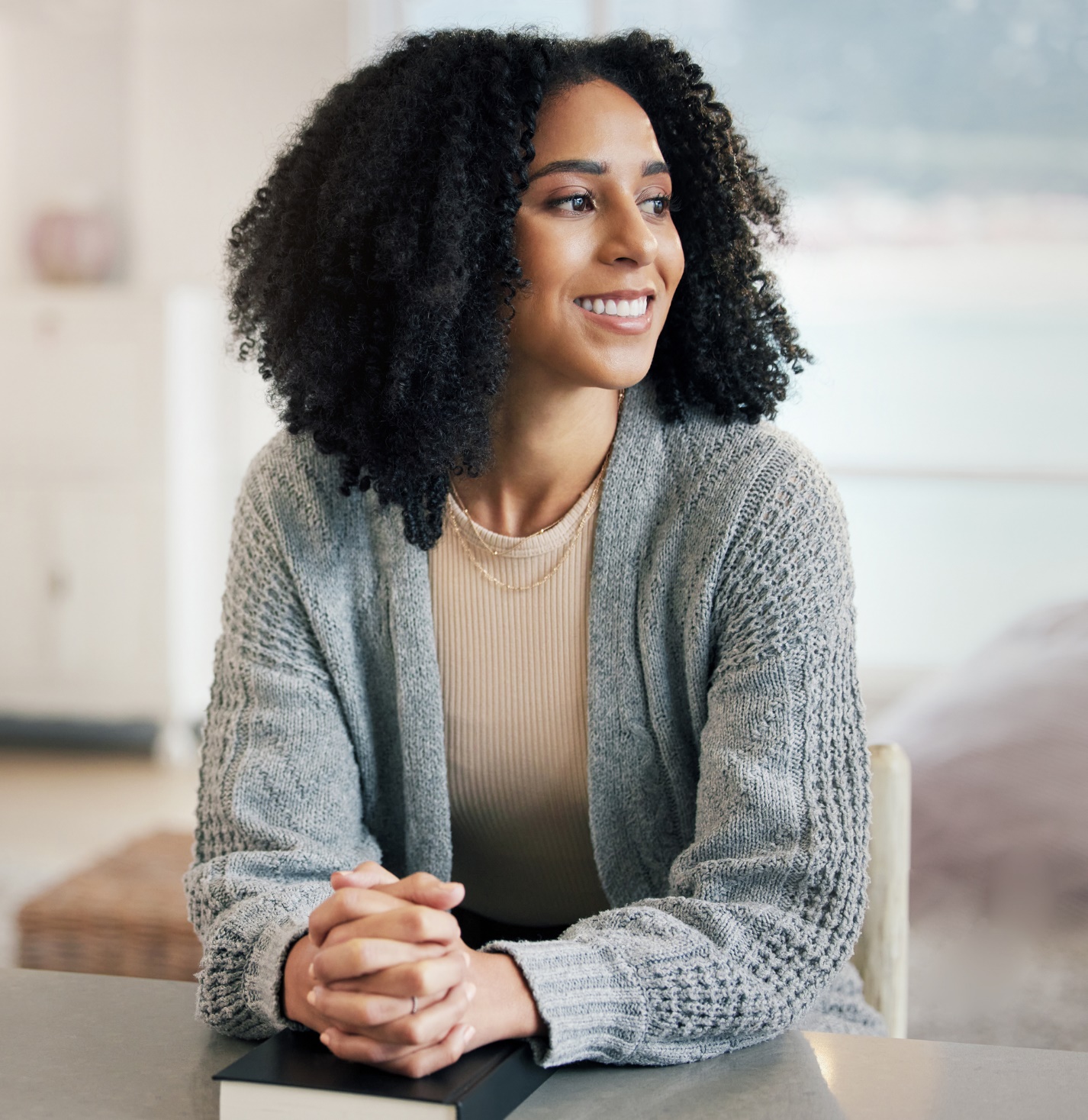 A person sitting at a table with her hands folded

Description automatically generated