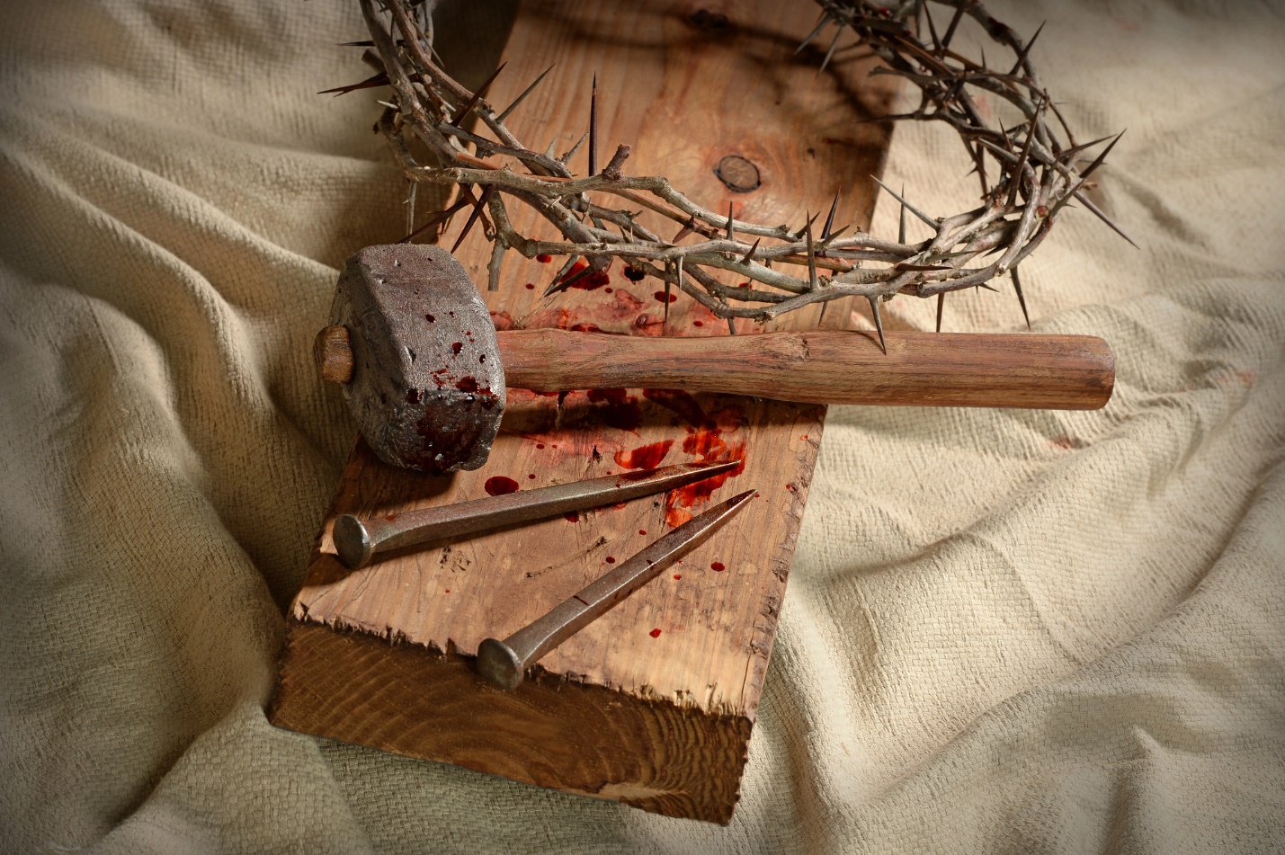 A crown of thorns and nails on a wooden surface

Description automatically generated