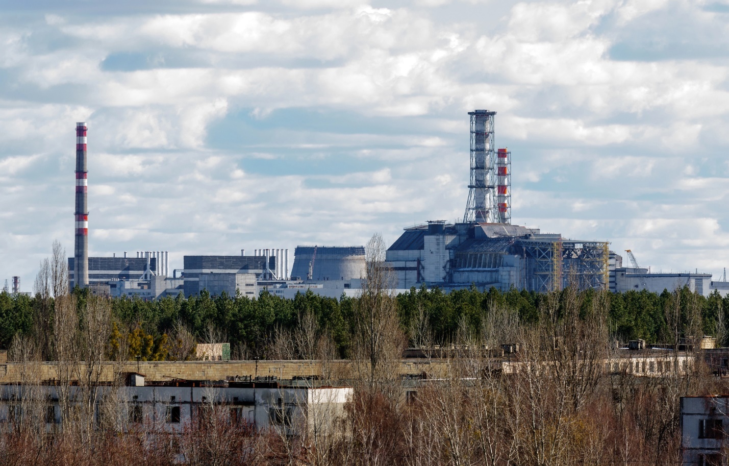 A factory with trees and a cloudy sky

Description automatically generated