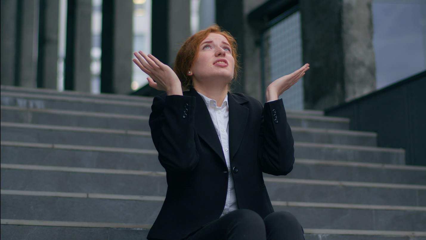 A person sitting on stairs with her hands up

Description automatically generated